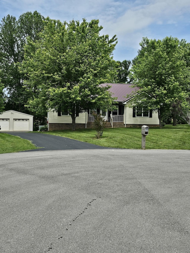 view of front of house featuring an outbuilding, a detached garage, a front yard, and metal roof