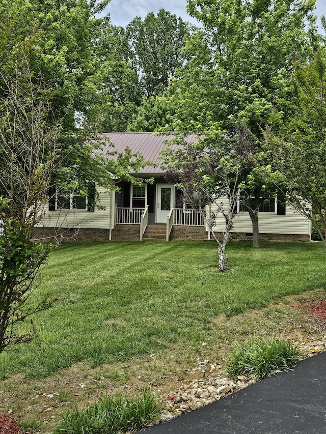 view of front facade featuring covered porch, a front yard, metal roof, and a standing seam roof