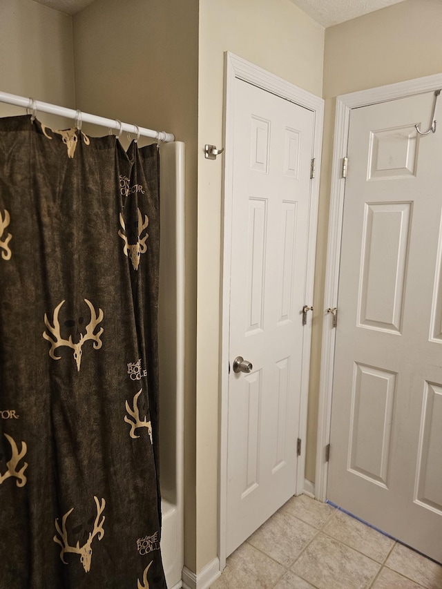 full bath with tile patterned floors, a shower with curtain, and baseboards