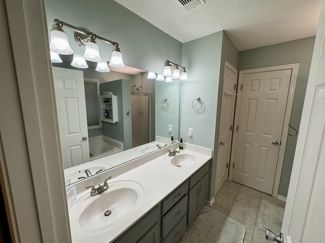 bathroom featuring a shower stall, tile patterned flooring, double vanity, a textured ceiling, and baseboards