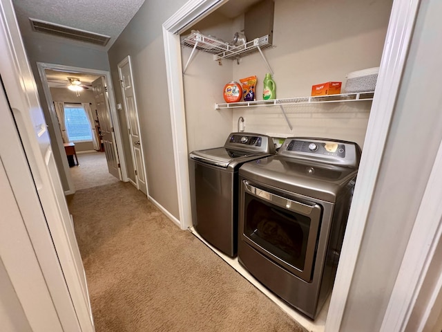 washroom featuring independent washer and dryer, carpet flooring, a textured ceiling, and baseboards