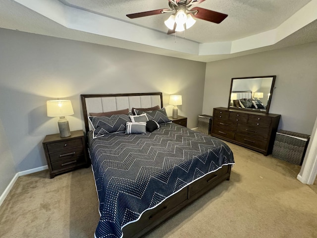 carpeted bedroom with a raised ceiling, baseboards, a textured ceiling, and ceiling fan
