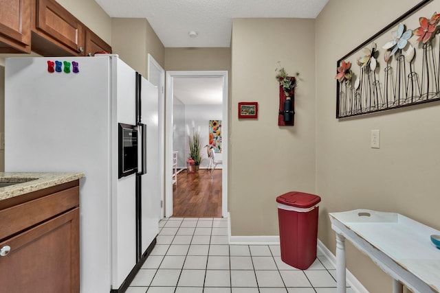 536 River St Unit 536, Chattanooga, TN 37405 - kitchen featuring white fridge with ice dispenser, brown cabinetry, light tile patterned floors, baseboards, and a textured ceiling