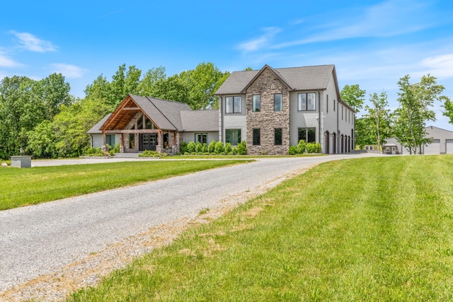 view of front of property with stone siding, a front lawn, and gravel driveway