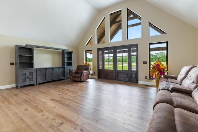 living area with light wood-style flooring, baseboards, and high vaulted ceiling