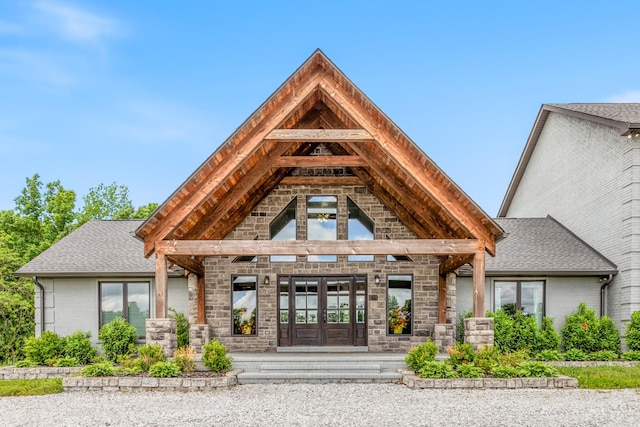 property entrance featuring french doors, stone siding, roof with shingles, and brick siding