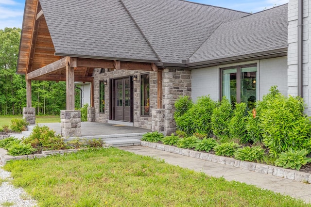 entrance to property with roof with shingles, stone siding, french doors, and covered porch