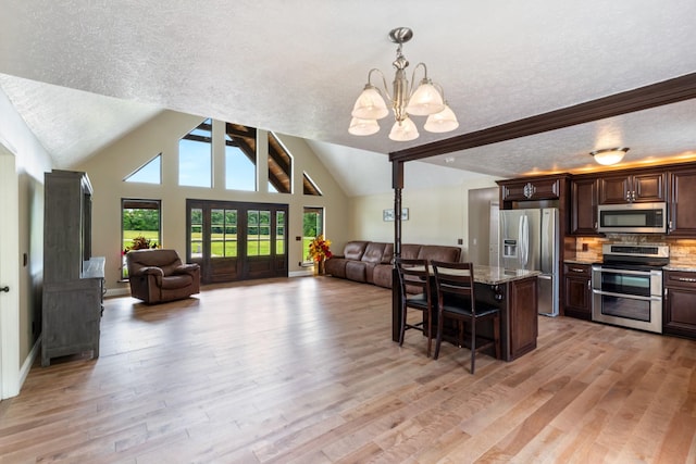 dining room with a textured ceiling, a chandelier, vaulted ceiling, and light wood-style flooring