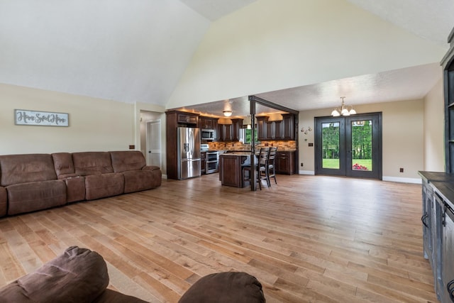 living area with a chandelier, high vaulted ceiling, and light wood-style floors