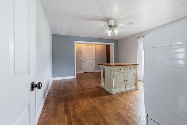 corridor with hardwood / wood-style floors, baseboards, and a textured ceiling