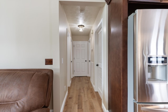 hall with light wood-style floors and baseboards