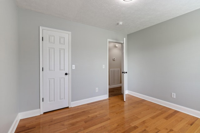 unfurnished bedroom with light wood-style flooring, baseboards, and a textured ceiling