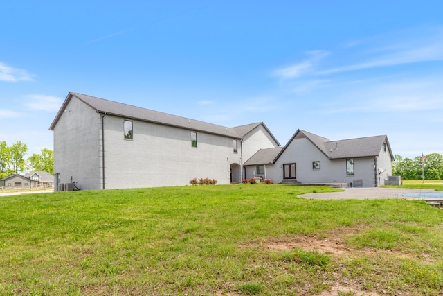 rear view of property with a lawn and central air condition unit
