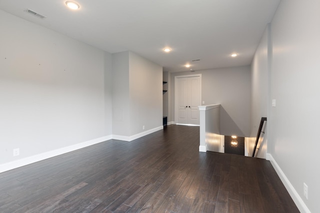 spare room with dark wood-style flooring, baseboards, and recessed lighting