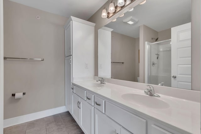 bathroom with toilet, baseboards, a stall shower, double vanity, and tile patterned floors