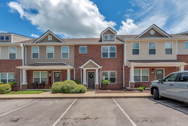 view of property with brick siding and uncovered parking