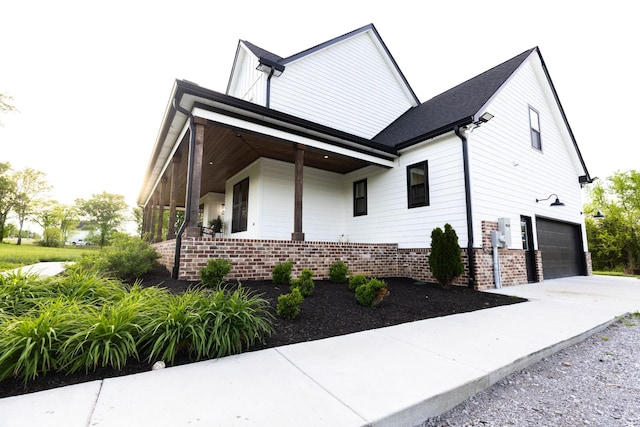 1325 Rogers Ln, Lebanon, TN 37087 - view of side of property featuring an attached garage, brick siding, concrete driveway, and covered porch