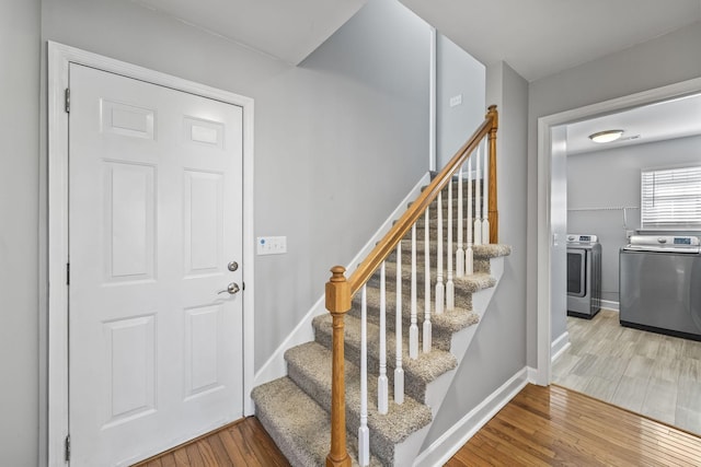 stairs featuring washing machine and dryer, wood finished floors, and baseboards