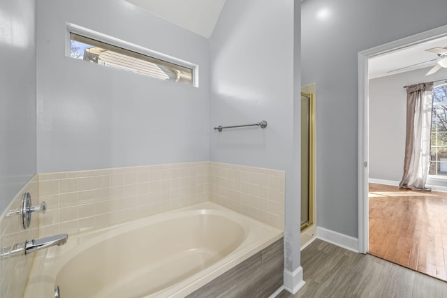 bathroom featuring a bath, baseboards, a shower stall, ceiling fan, and wood finished floors