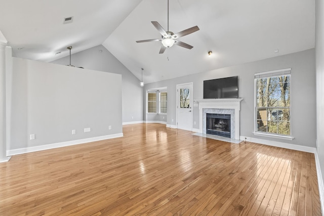 unfurnished living room with a ceiling fan, light wood-type flooring, a fireplace, high vaulted ceiling, and baseboards