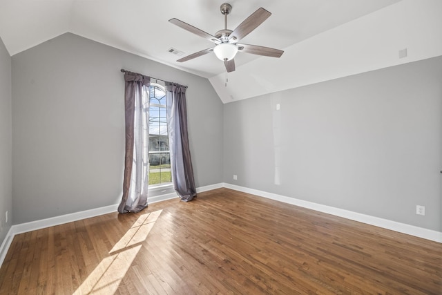 empty room with lofted ceiling, a ceiling fan, hardwood / wood-style floors, and baseboards