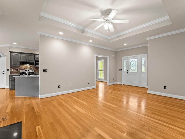 416 Overlook Cir, Tullahoma, TN 37388 - unfurnished living room featuring a tray ceiling, light wood finished floors, ceiling fan, recessed lighting, and a sink