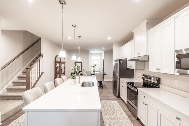 124 Great Falls Ct, Gallatin, TN 37066 - kitchen featuring appliances with stainless steel finishes, under cabinet range hood, a sink, an island with sink, and light wood-style floors