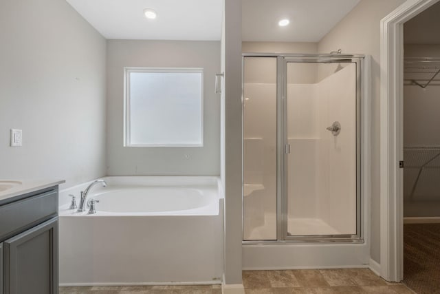 full bath featuring a shower stall, a walk in closet, a bath, and vanity
