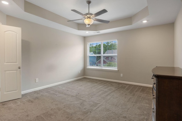 carpeted spare room featuring recessed lighting, baseboards, a ceiling fan, and a raised ceiling