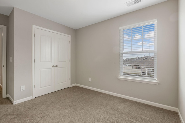 unfurnished bedroom with carpet flooring, baseboards, and a closet