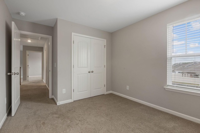 unfurnished bedroom featuring attic access, light colored carpet, multiple windows, and a closet