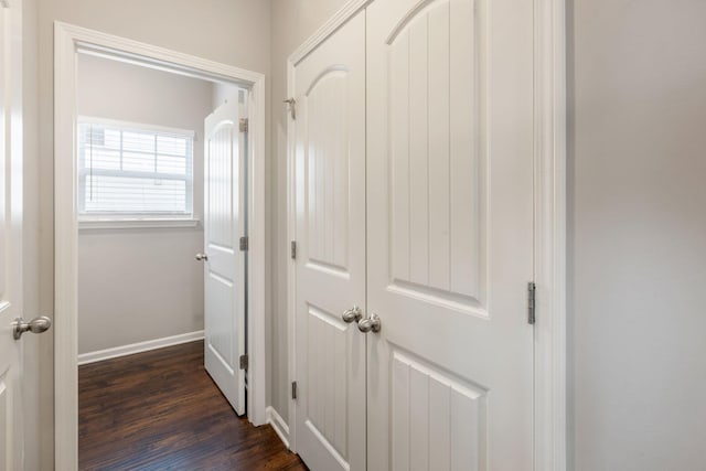 hall with dark wood-style flooring and baseboards