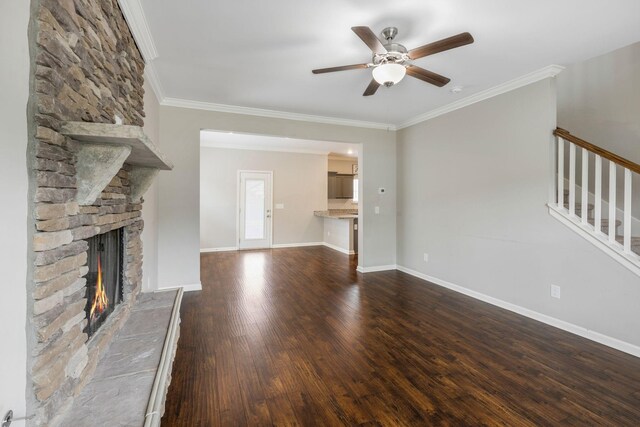 unfurnished living room featuring a ceiling fan, a fireplace, dark wood-style floors, stairway, and ornamental molding