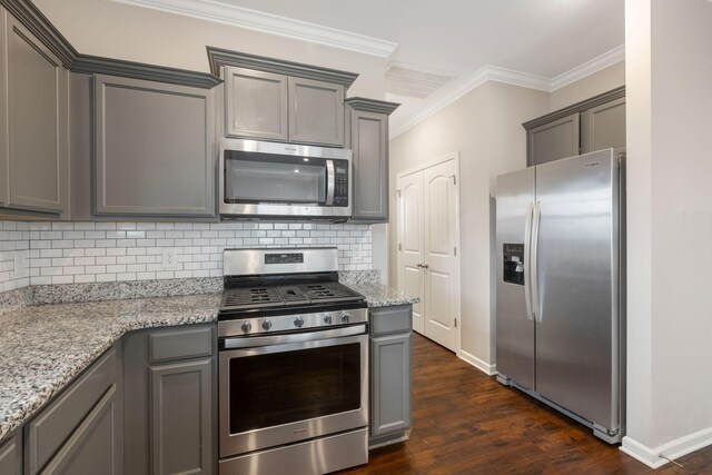 kitchen with stainless steel appliances, gray cabinets, dark wood finished floors, decorative backsplash, and crown molding