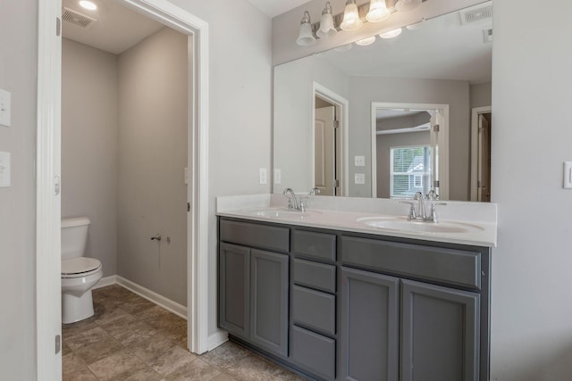 full bathroom featuring toilet, double vanity, and baseboards