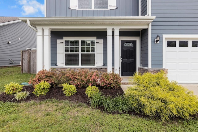 doorway to property featuring board and batten siding, a garage, stone siding, and a porch