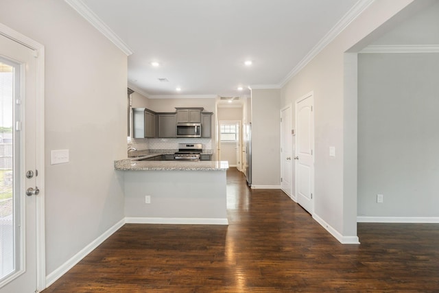 kitchen featuring stainless steel appliances, gray cabinetry, decorative backsplash, dark wood finished floors, and a peninsula