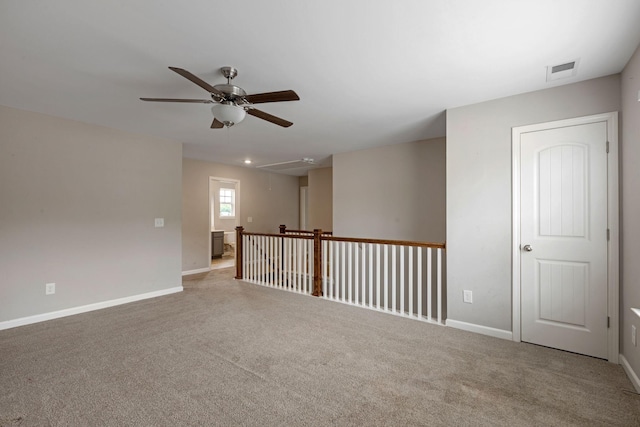 spare room featuring ceiling fan, carpet floors, baseboards, and attic access