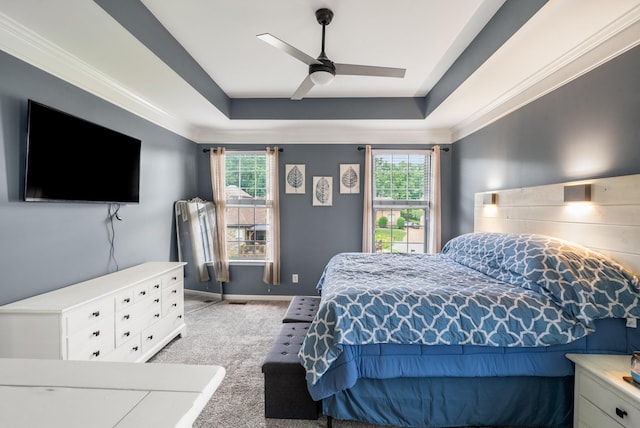 bedroom with light carpet, a raised ceiling, multiple windows, a ceiling fan, and crown molding