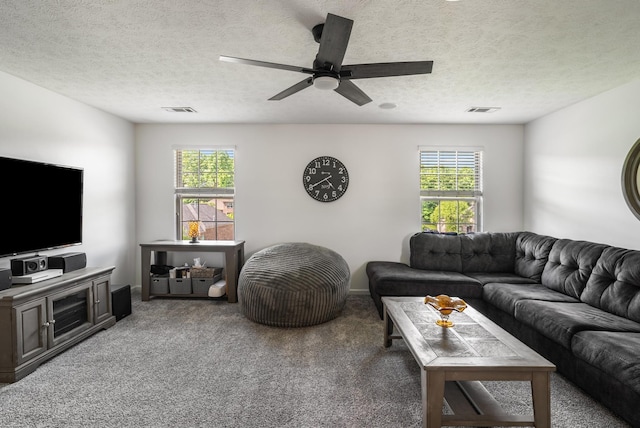 carpeted living room with healthy amount of natural light, ceiling fan, and a textured ceiling