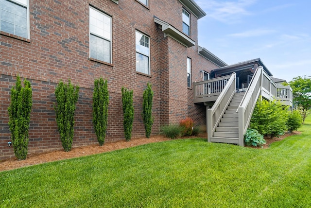 back of house featuring a yard, stairway, brick siding, and a deck
