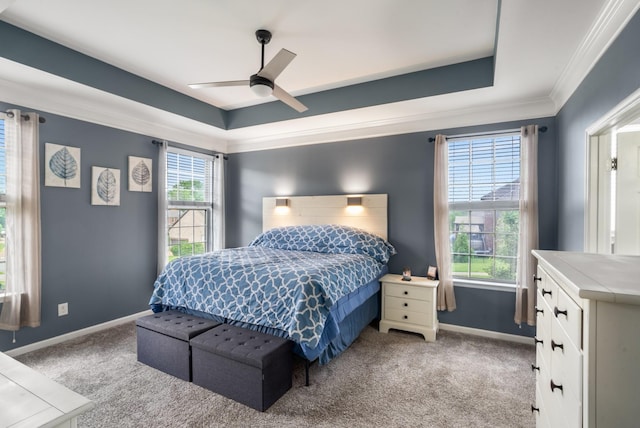 carpeted bedroom with crown molding, baseboards, a tray ceiling, and a ceiling fan