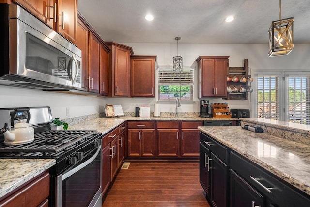 kitchen featuring appliances with stainless steel finishes, a sink, dark wood-style floors, recessed lighting, and decorative light fixtures