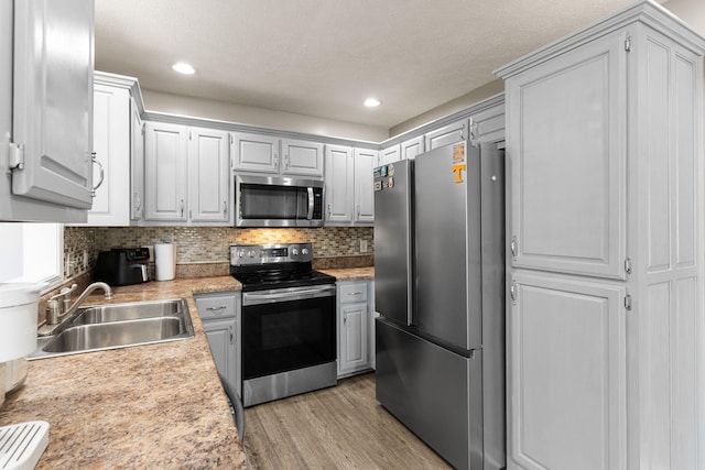 158 Cornerstone Blvd, Portland, TN 37148 - kitchen with appliances with stainless steel finishes, a sink, light countertops, light wood finished floors, and backsplash