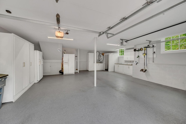 garage featuring white refrigerator with ice dispenser and a garage door opener