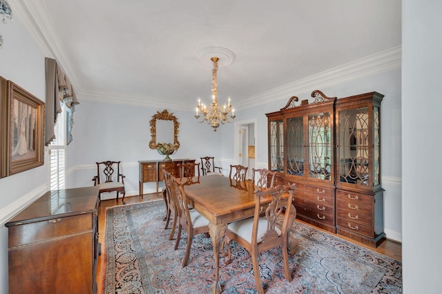 dining area featuring a chandelier, crown molding, and wood finished floors