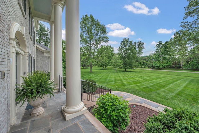 view of grassy yard with a porch and view of scattered trees