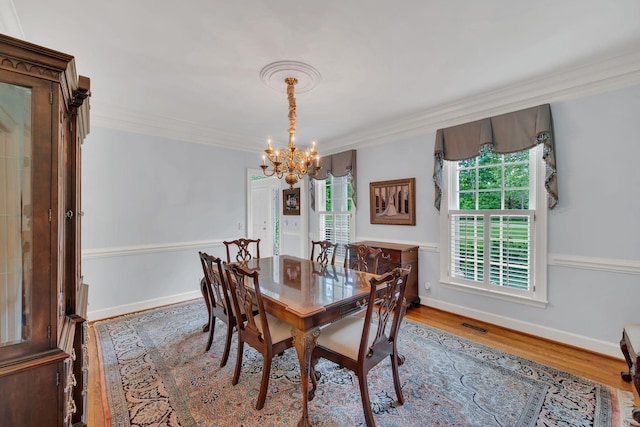 dining area featuring a chandelier, wood finished floors, and crown molding