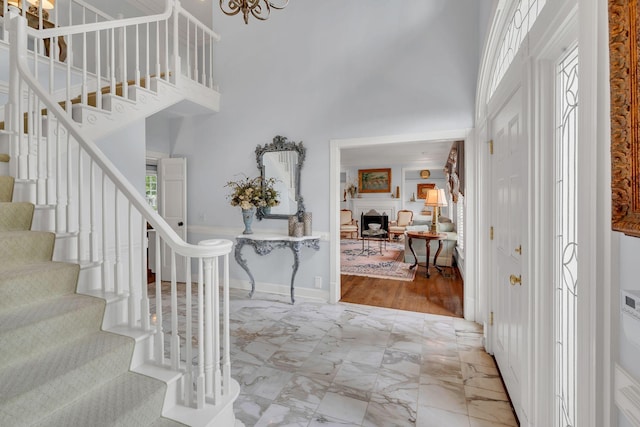 entryway featuring a high ceiling, stairway, plenty of natural light, and marble look tile flooring