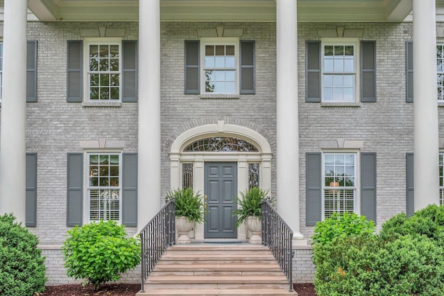 entrance to property with a porch and brick siding